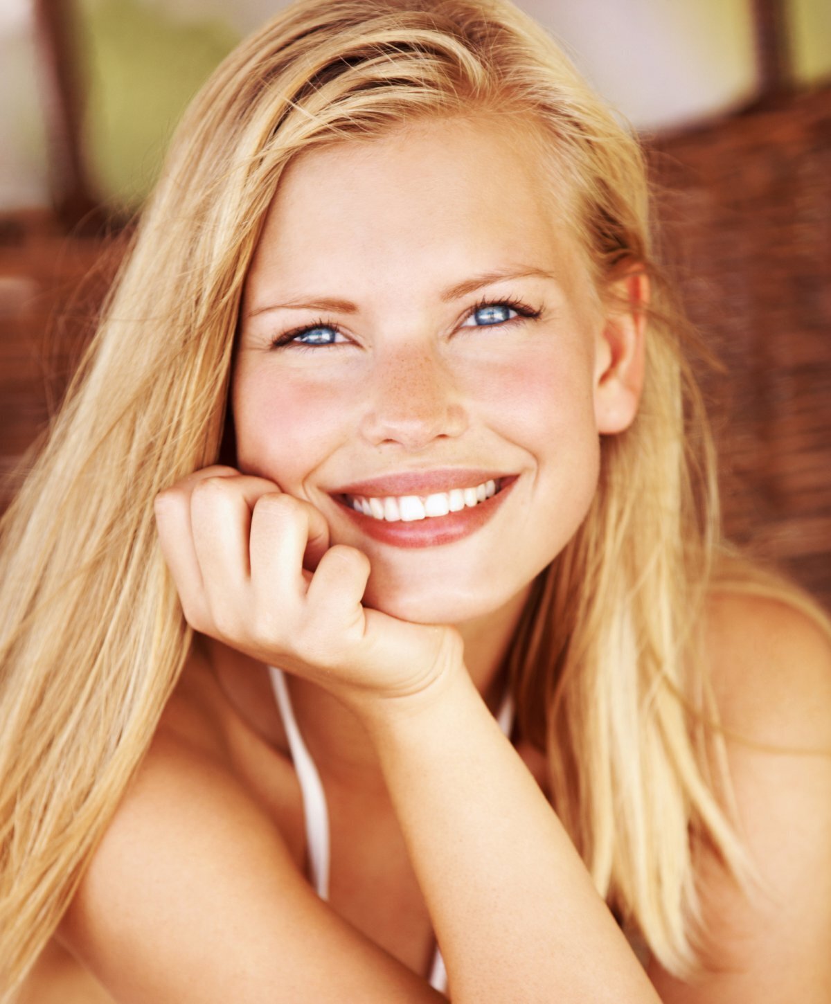 blonde Grand Rapids otoplasty patient model smiling and resting her chin on her hand