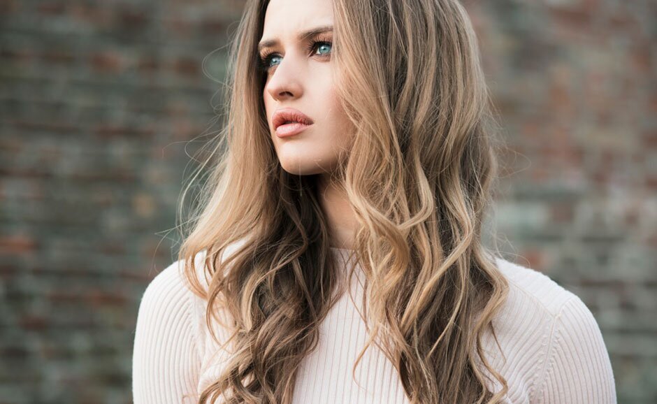 med spa patient model in white sweater standing against brick wall